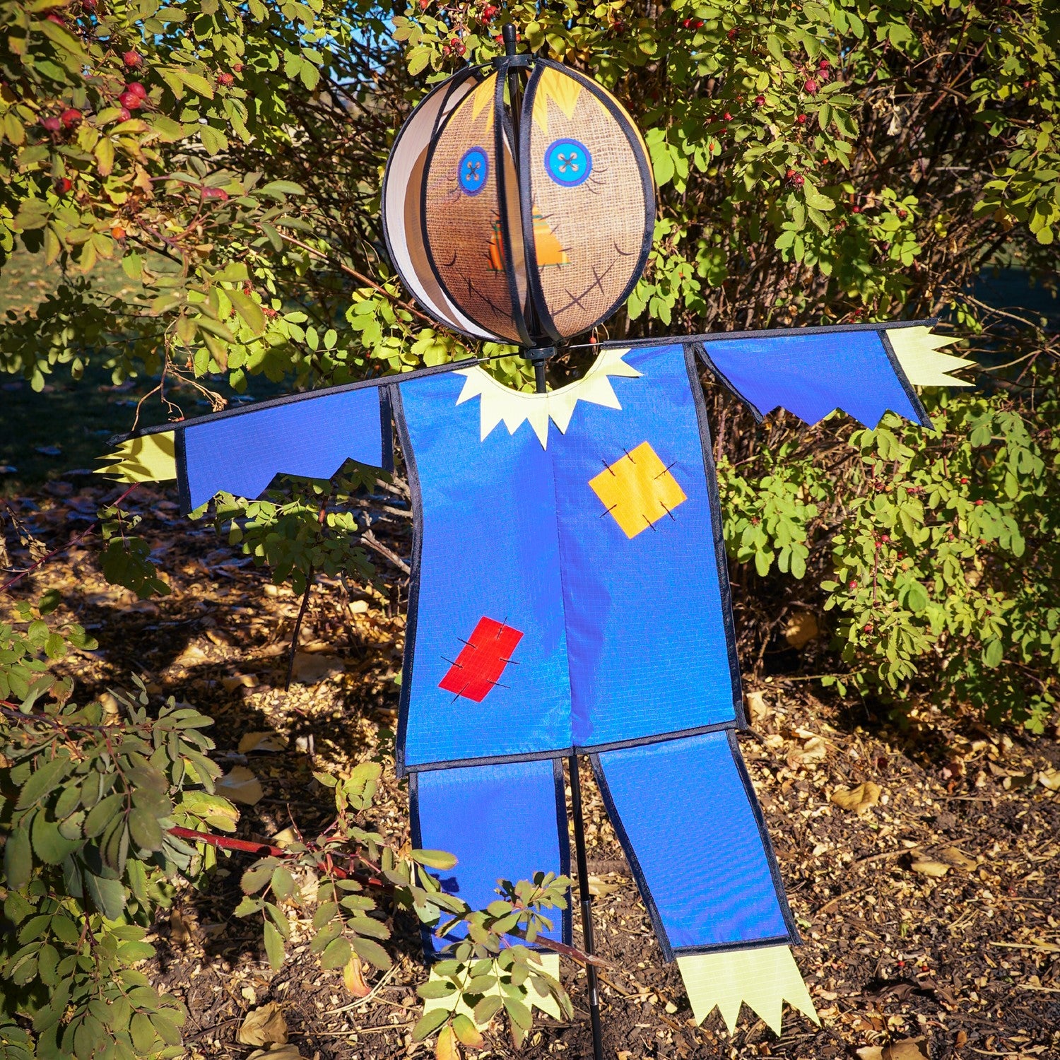 Colorful Scarecrow Ground Ball Spinner spinning in a garden setting, showcasing a friendly face with vibrant colors and durable design.