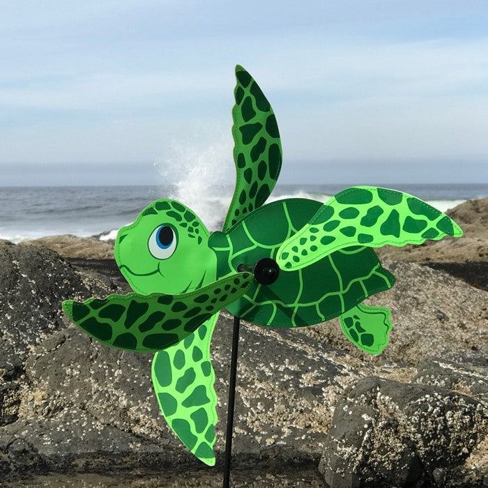 Sea Turtle Baby Whirligig in colorful design, featuring counter-rotating fins, displayed in a sunny garden setting, enhancing the outdoor atmosphere.