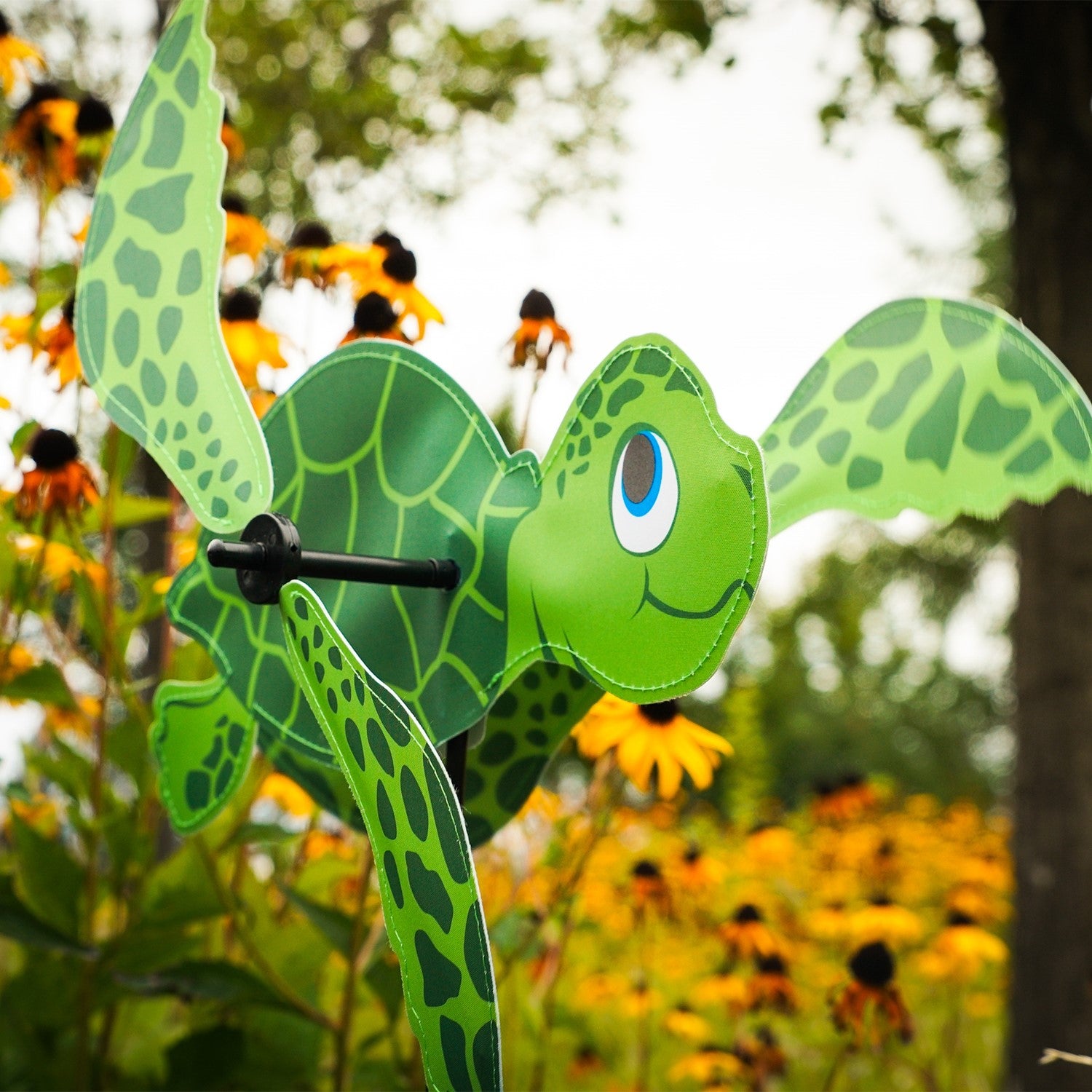 Sea Turtle Baby Whirligig in colorful design, featuring counter-rotating fins, displayed in a sunny garden setting, enhancing the outdoor atmosphere.