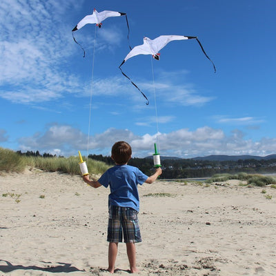 Seagull Kite with detailed design and black streamer tails soaring against a blue sky during outdoor activity, perfect for family fun.
