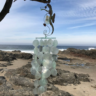 Seahorse Capiz Breeze Wind Chime featuring vibrant Capiz shells shaped like seahorses, hanging elegantly in a garden setting.