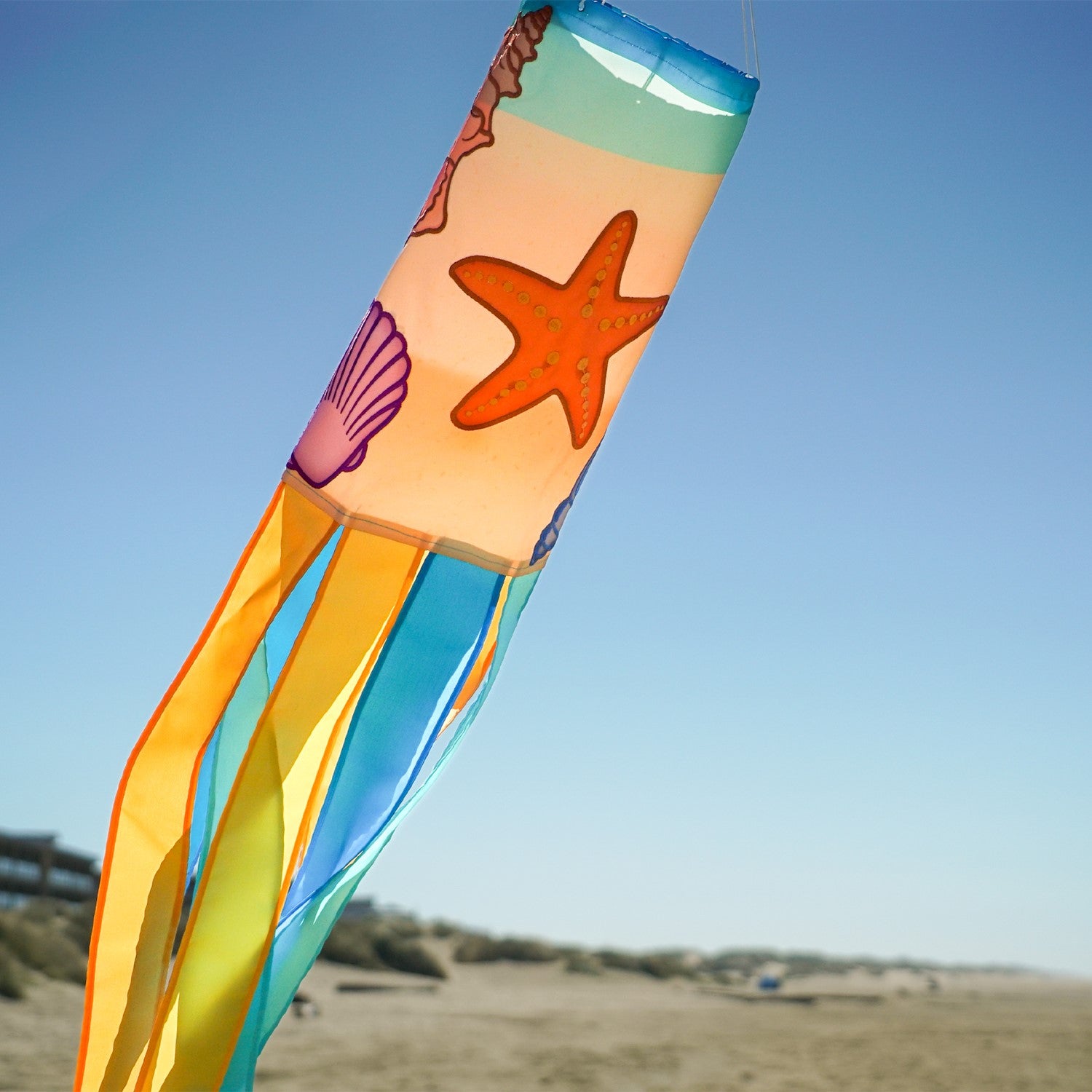 Seashell 40-inch windsock featuring colorful applique designs and tails fluttering outdoors, adding a coastal charm to any garden space.