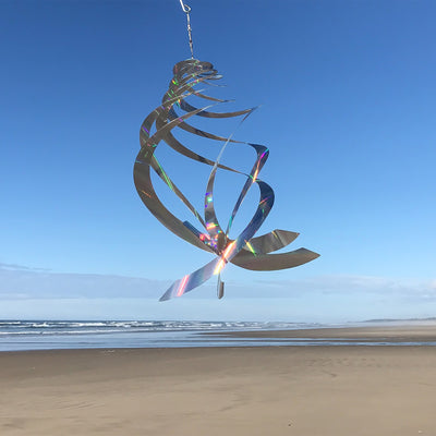 Sheen Crystal Spinner made of holographic Mylar, featuring five spinning blades reflecting rainbow colors, hanging in a garden with sunlight.
