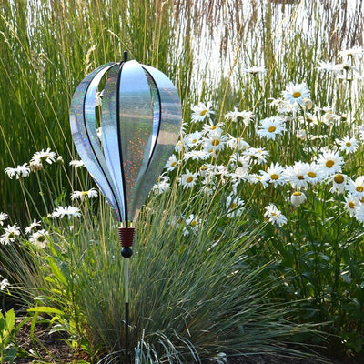 Silver Sparkle 6-Panel Hot Air Balloon Ground Spinner made of shimmering Mylar, elegantly displayed in a garden setting under sunlight.
