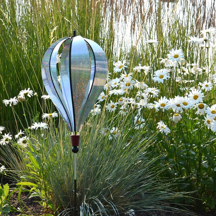 Silver Sparkle 6-Panel Hot Air Balloon Ground Spinner made of shimmering Mylar, elegantly displayed in a garden setting under sunlight.