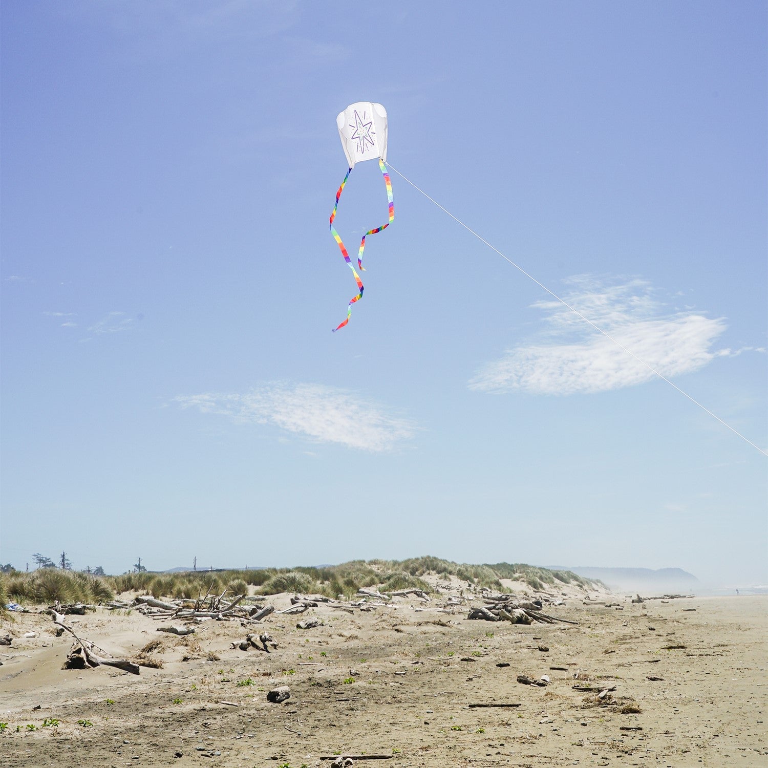 Sled Coloring Kite made of white ripstop fabric, featuring rainbow-striped tails, ready for personal decoration with crayons for an enjoyable outdoor experience.