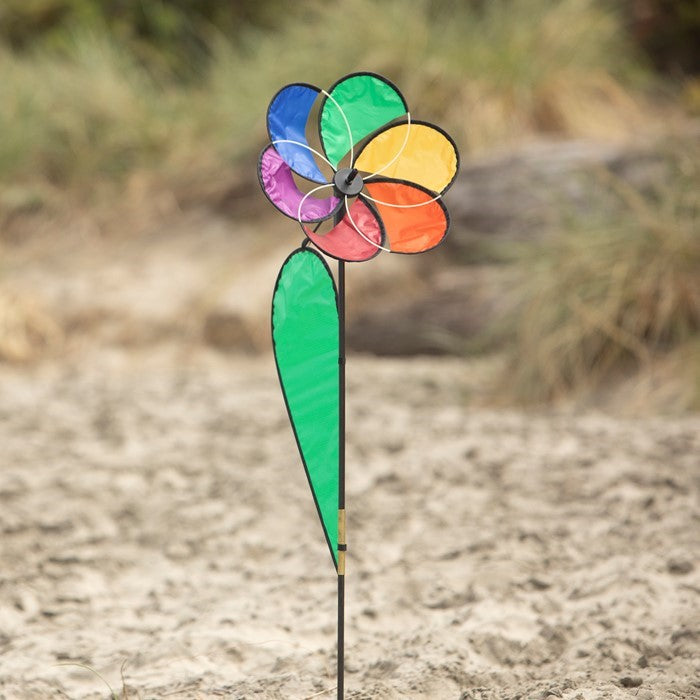 Small Rainbow Daisy Spinner featuring colorful petals and a two-wheeled structure, designed for outdoor display in a garden setting.