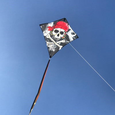 Smokin' Pirate 30" Diamond Kite with a Jolly Roger design flying against a clear blue sky, featuring three long colorful tails.