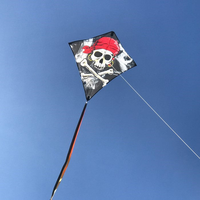 Smokin' Pirate 30" Diamond Kite with a Jolly Roger design flying against a clear blue sky, featuring three long colorful tails.