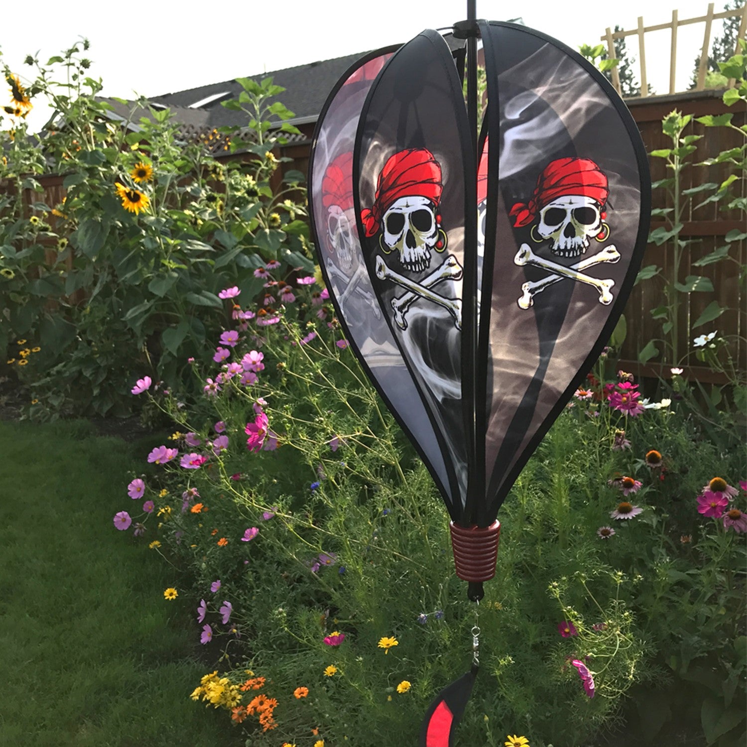 Smokin' Pirate Hot Air Balloon spinning in the breeze with a skull and crossbones design, adding vibrant decor to an outdoor garden setting.