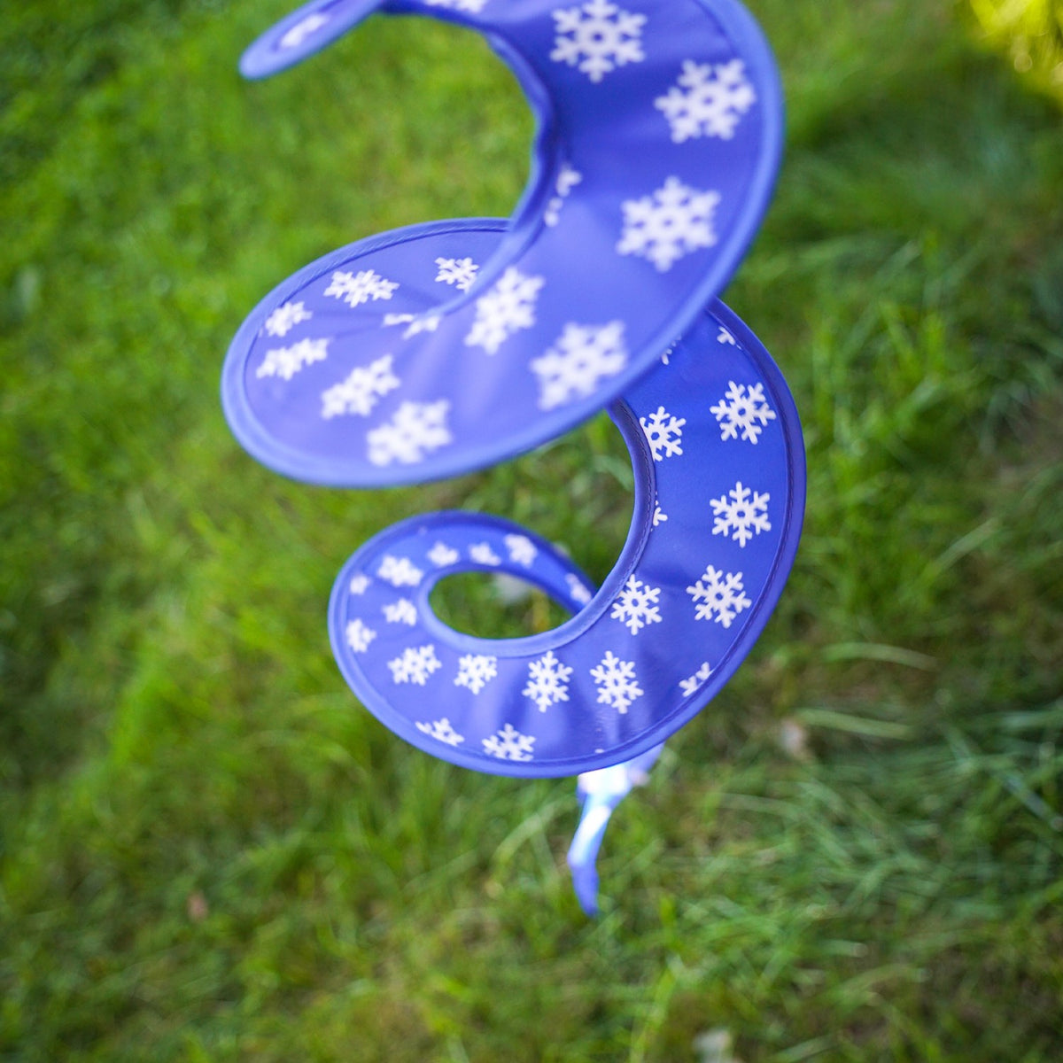 Snowman with Hat Hanging Ball Spinner in a garden setting, showcasing colorful panels and a cheerful, embroidered face, perfect for winter decoration.