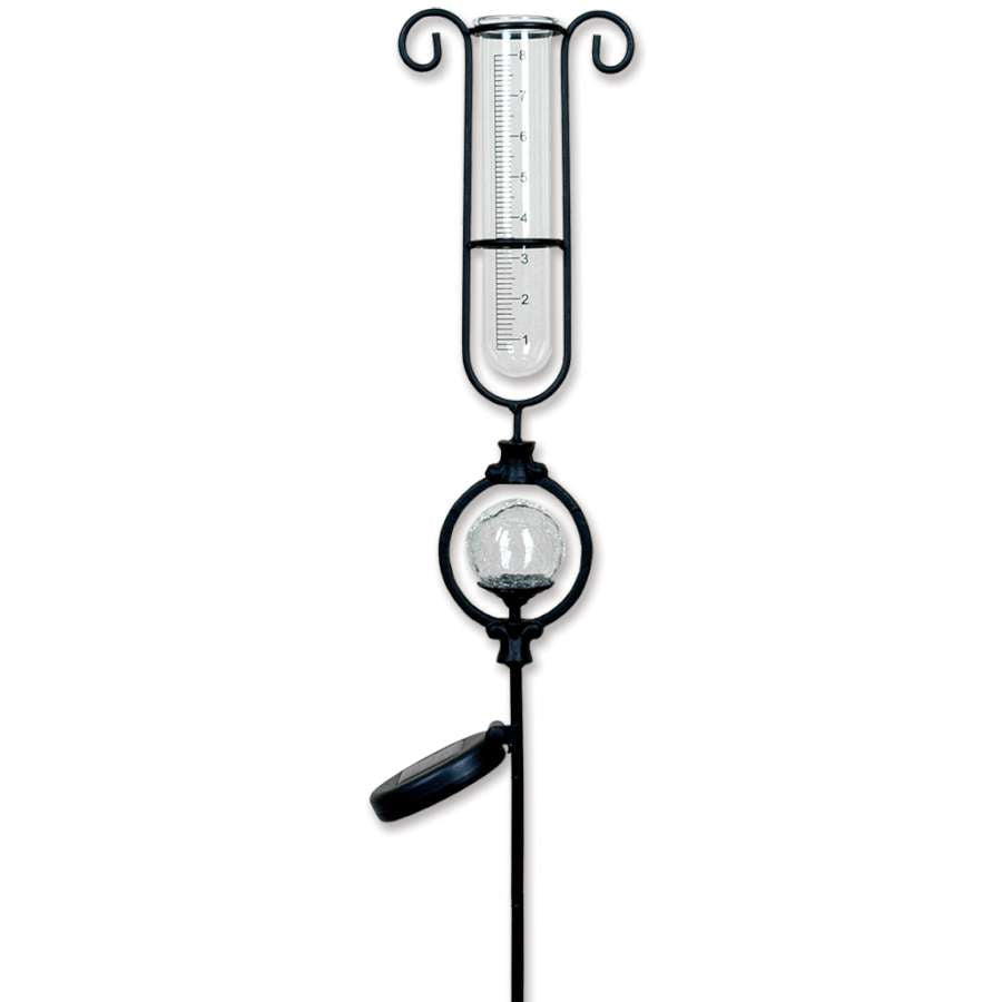 Solar Rain Gauge measuring rainfall with color-changing LED lights illuminating at night, set in a vibrant garden.