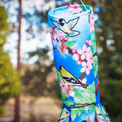 Songbird 40\" Illusion Windsock with colorful printed design and embroidered details, hanging freely in an outdoor garden setting.