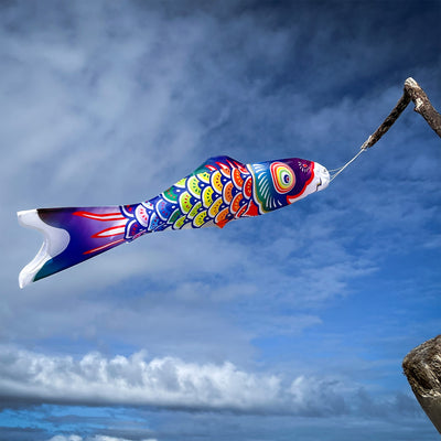 3' Spectrum Koi Fishsock in vibrant rainbow colors hanging gracefully in a garden setting, showcasing its whimsical design and lightweight construction.