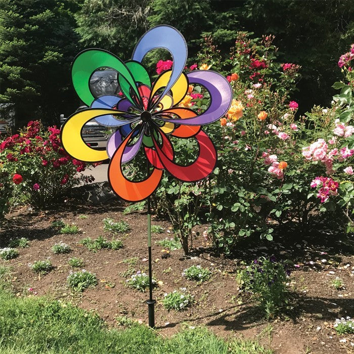 Spectrum Triple Windee Wheelz colorful garden spinner featuring three rotating rainbow flowers, displayed outdoors in a sunny garden setting.