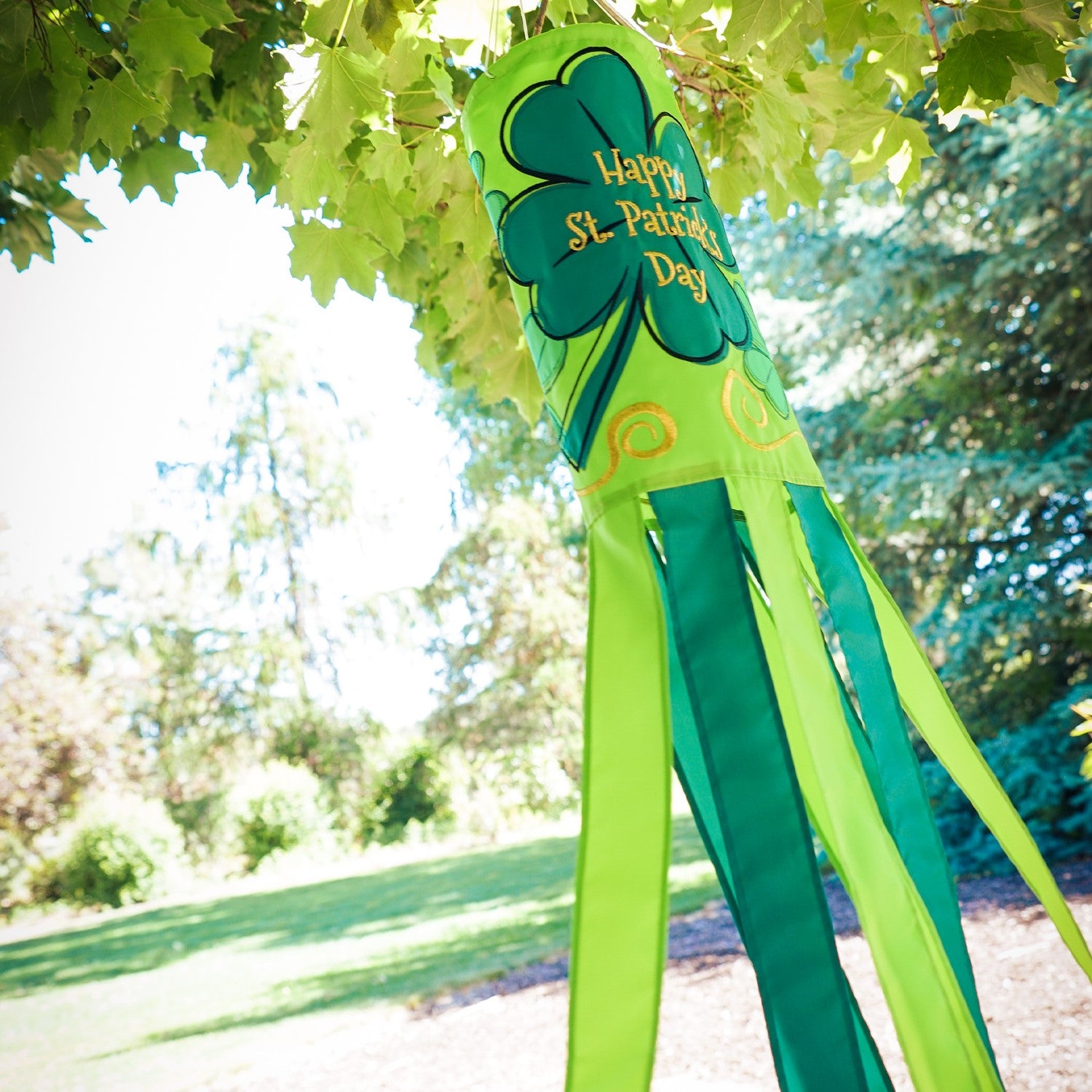 St Patrick's Day 40-inch windsock featuring vibrant four-leaf clover designs and color-coordinated tails, hanging outdoors in a garden.