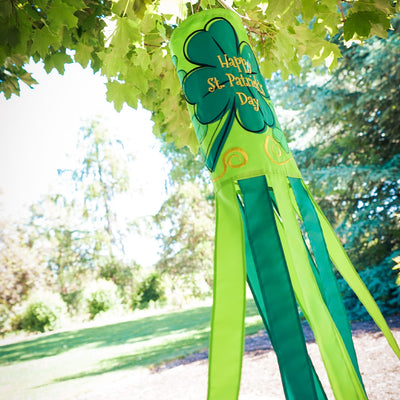 St Patrick's Day 40-inch windsock featuring vibrant four-leaf clover designs and color-coordinated tails, hanging outdoors in a garden.