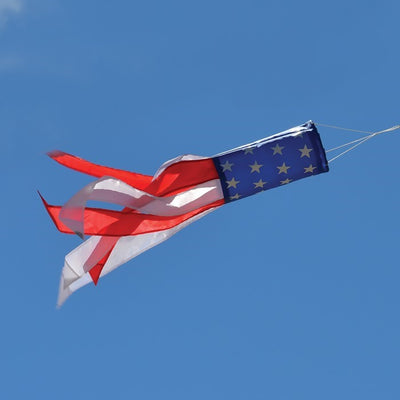 Stars & Stripes 24\" Windsock with vibrant red, white, and blue colors featuring silk-screened stars, hanging gracefully outdoors.