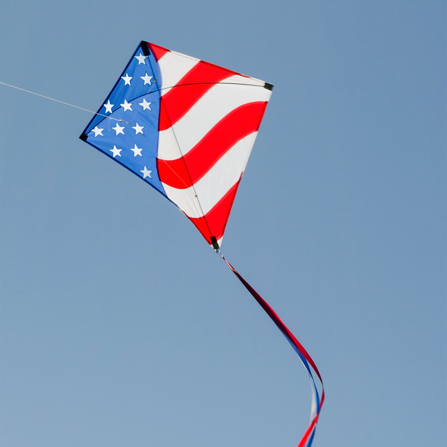 Stars & Stripes 30-inch Diamond Kite with red, white, and blue design, flying high in the sky with decorative tails.