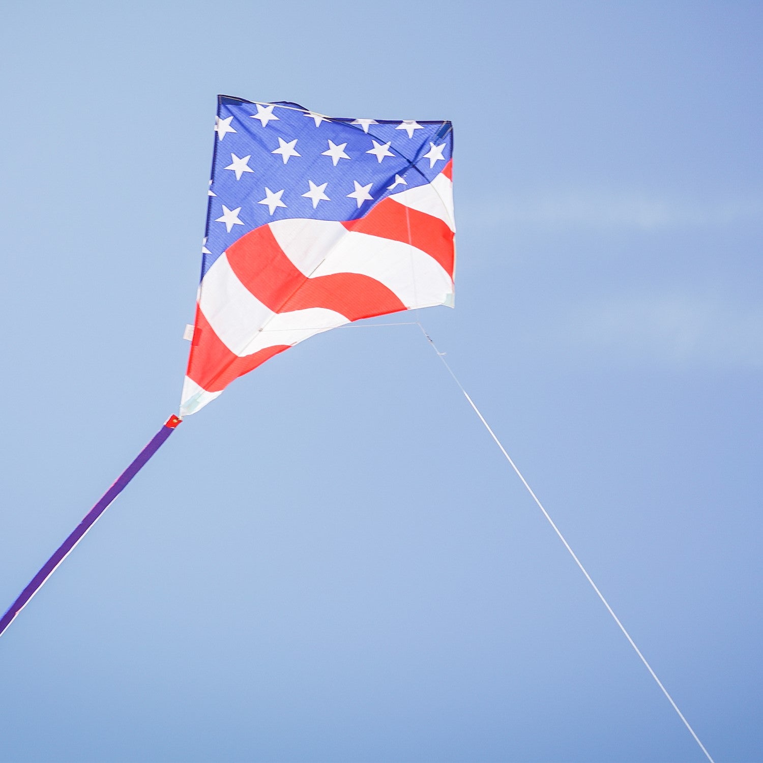 Stars & Stripes 30-inch Diamond Kite with red, white, and blue design, flying high in the sky with decorative tails.