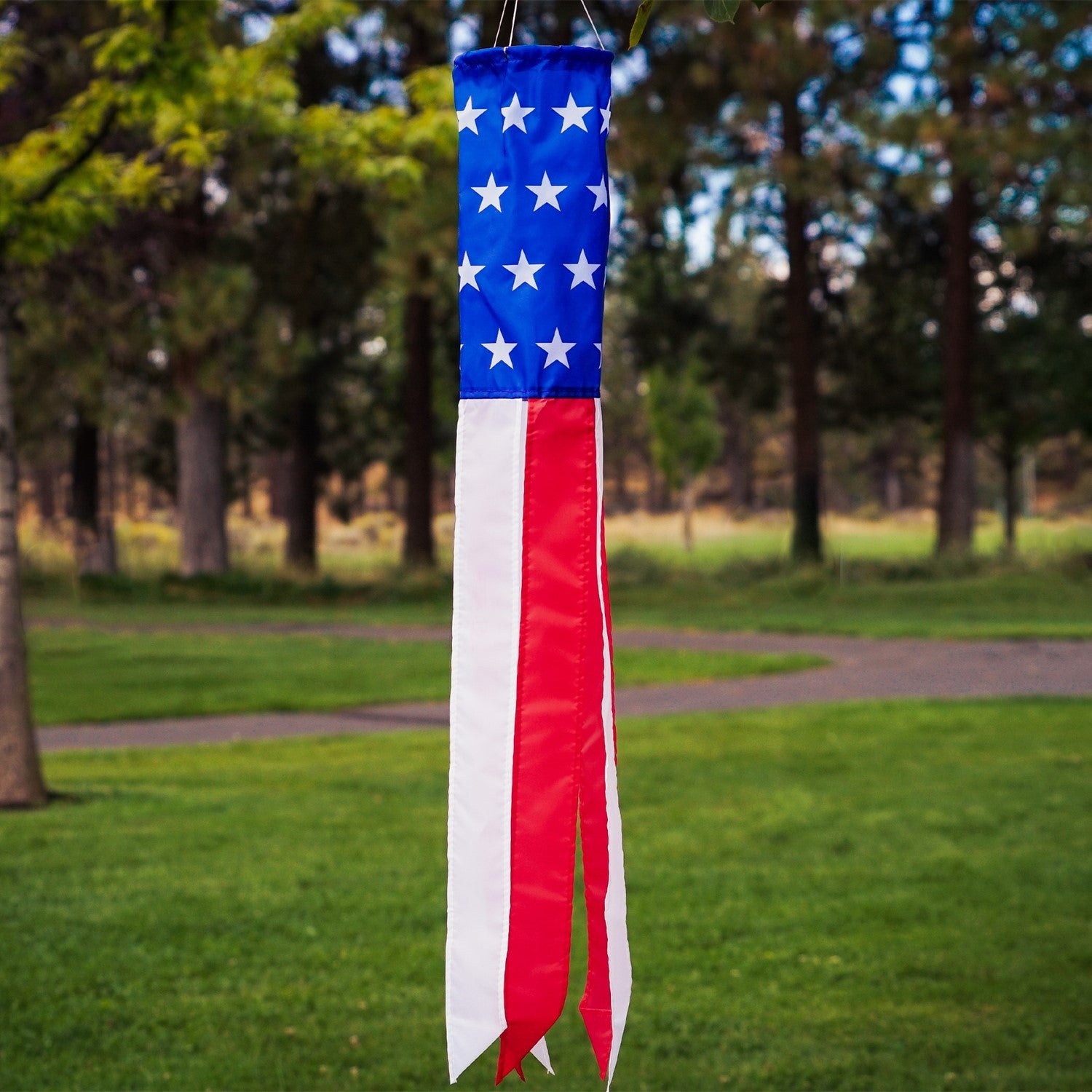 33-inch Stars and Stripes windsock in vibrant red, white, and blue displayed outdoors, showcasing silk-screened stars and colorful tails.