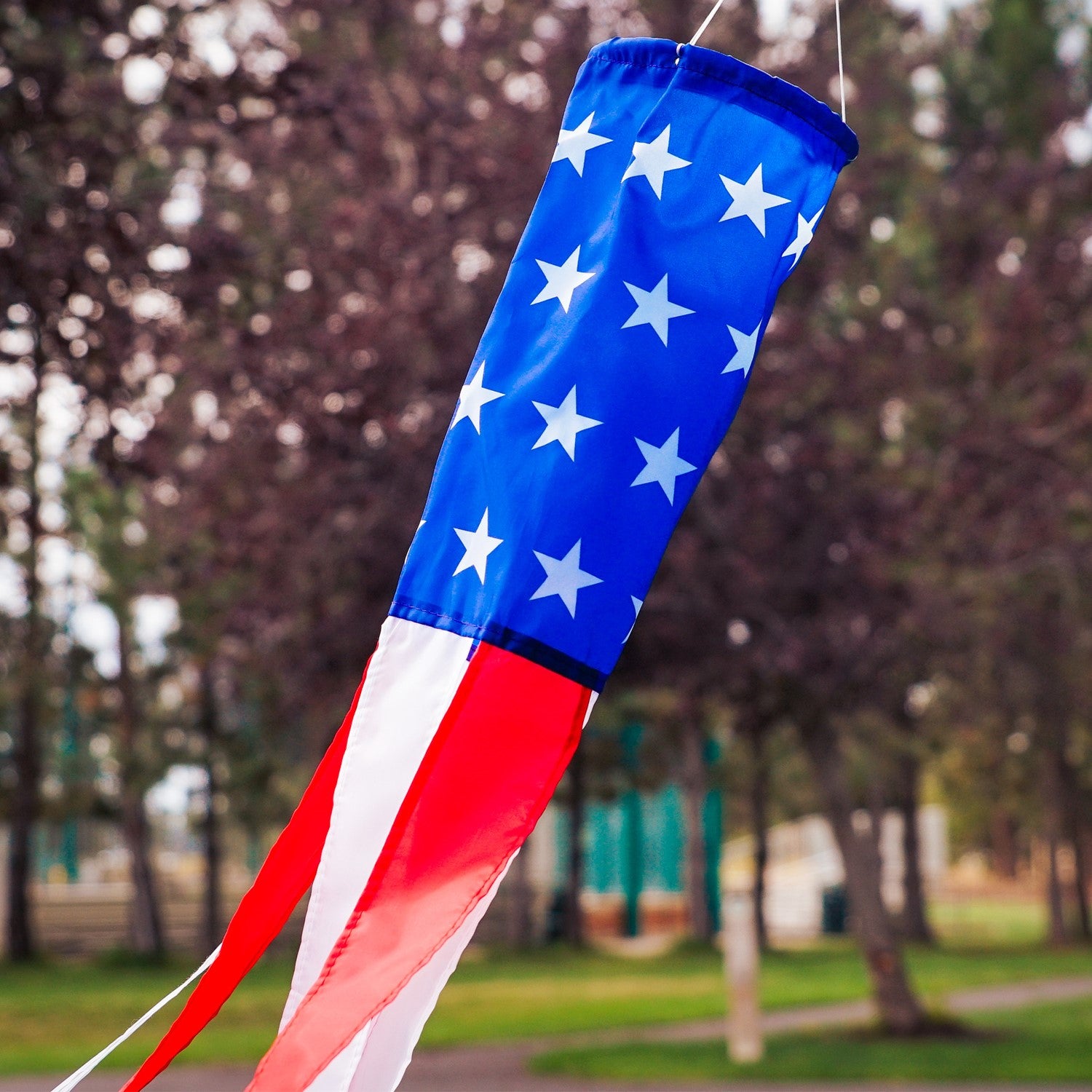 33-inch Stars and Stripes windsock in vibrant red, white, and blue displayed outdoors, showcasing silk-screened stars and colorful tails.