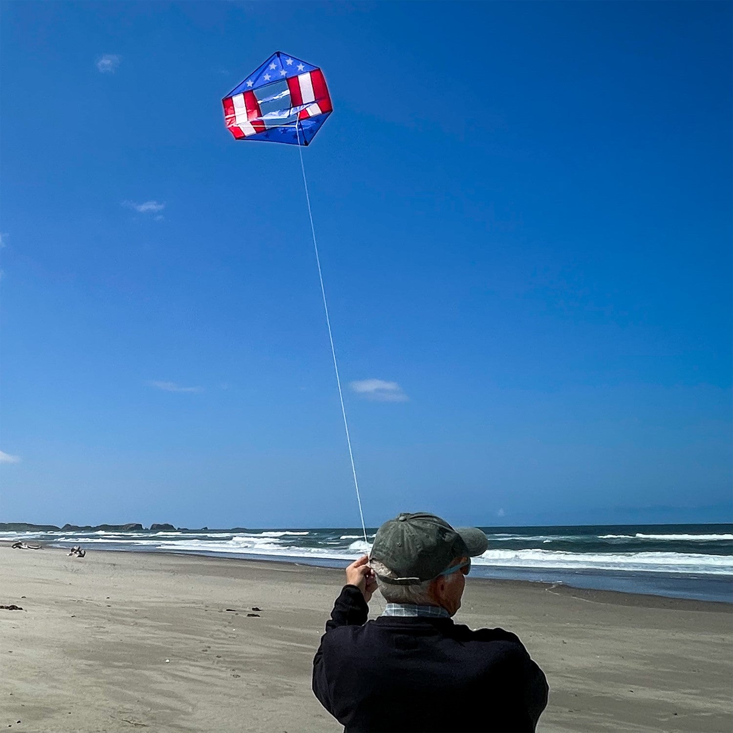 Stars & Stripes Winged Box Kite with a vibrant red, white and blue design soaring against a clear blue sky during an outdoor event.