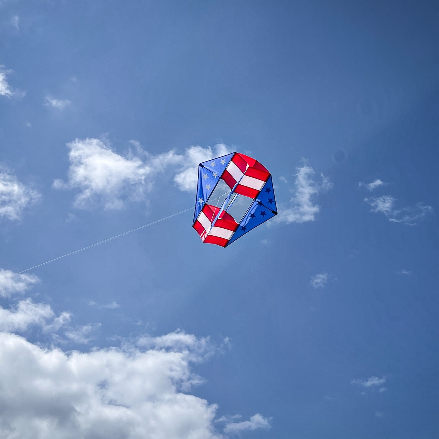 Stars & Stripes Winged Box Kite with a vibrant red, white and blue design soaring against a clear blue sky during an outdoor event.