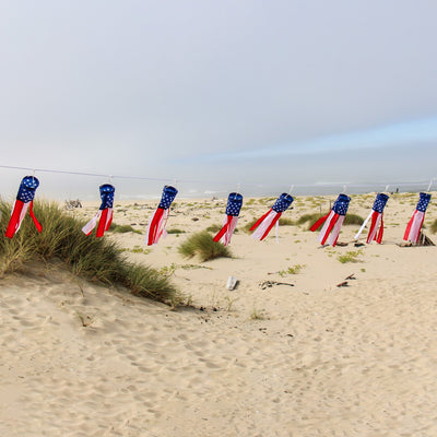 Stars & Stripes String of Babysocs featuring eight 12-inch windsocks swaying in the breeze, showcasing vibrant patriotic colors outdoors.