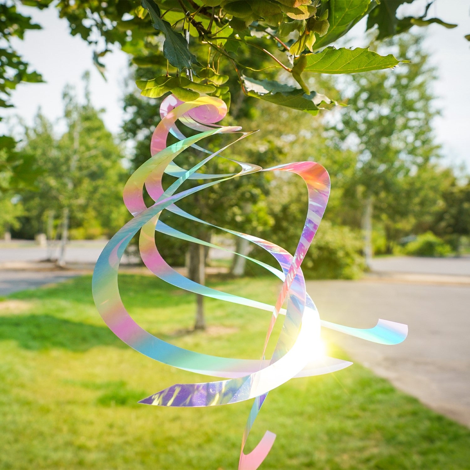 Vibrant Striped Iridescent Crystal Spinner made of Mylar, hanging outdoors with colorful reflections in sunlight, perfect for garden decor.