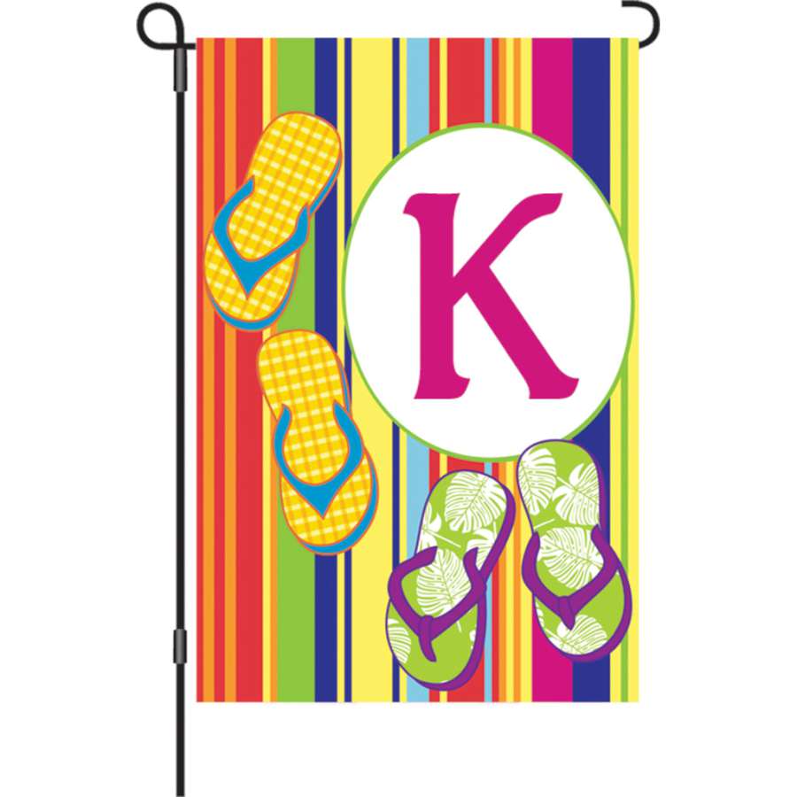 12 in. Summer Monogram Flag - K displayed in a garden, featuring a colorful initial 'K' design, enhancing outdoor decor vibrancy.
