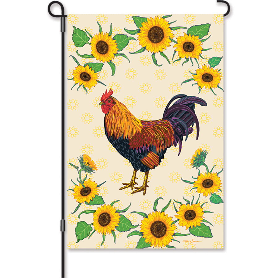 12 in. Sunflower Rooster garden flag featuring a colorful rooster surrounded by sunflowers, displayed in an outdoor garden setting.
