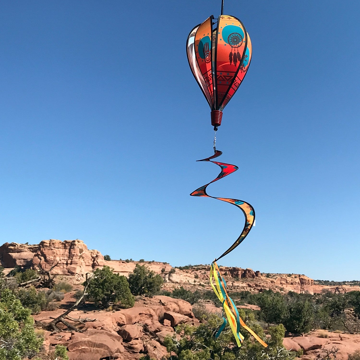 S.W. Icons 6-Panel Hot Air Balloon spinner displayed in a garden, showcasing vibrant Southwestern designs in motion as it spins in the breeze.