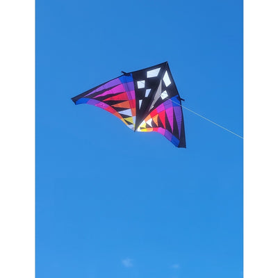Sweet 16 Delta Kite - Sunset Check, featuring vibrant colors and a large design, soaring high against an open blue sky during outdoor flight.