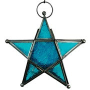 Teal 5-Point Star Hanging Tealight Lantern with textured glass panels and metal accents, suspended outdoors against a scenic backdrop.