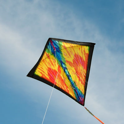 Tie Dye 30 inch Diamond Kite flying high in the sky with vibrant colors and 12-foot streamer tails swaying in the wind.