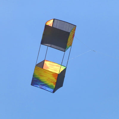 Tie Dye Box Kite flying high against a blue sky, showcasing its vibrant tie-dye design and sturdy fiberglass structure.