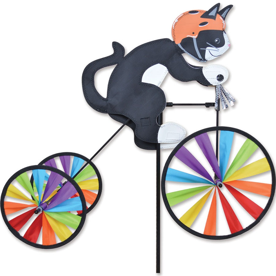 Tricycle Spinner featuring a tuxedo cat riding on a colorful tricycle with shiny silver tassels, showcased in a vibrant outdoor garden.