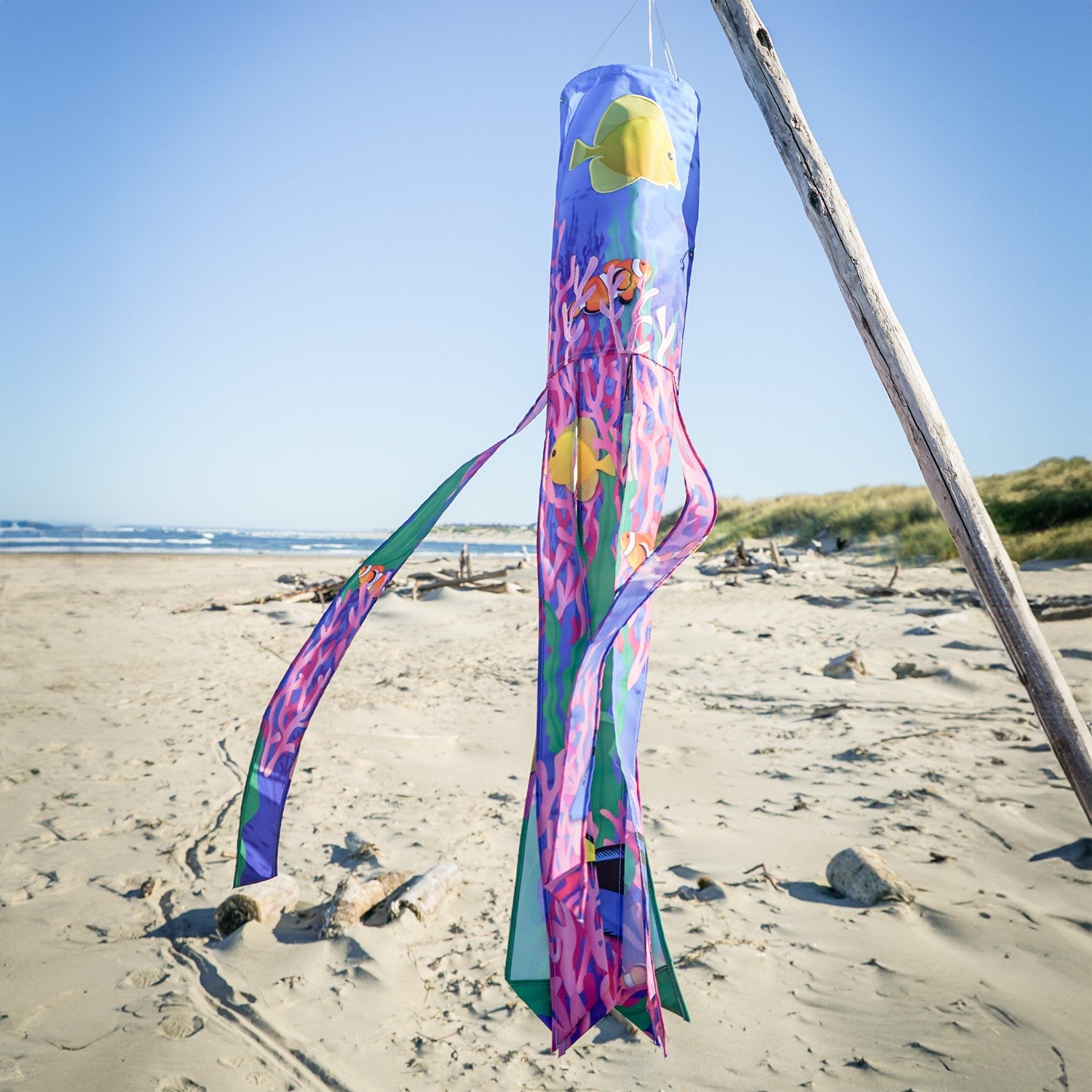 Tropical Fish 40\" Illusion Windsock displaying a vivid fish design and colorful tails, fluttering in a gentle breeze in a garden setting.