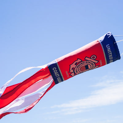 U.S. Coast Guard 40 inch windsock with detailed appliqued graphics and embroidered accents, fluttering outdoors in a garden setting.