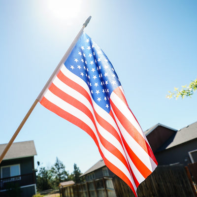 12x18 inch U.S. Stick Flags on wooden sticks, designed for outdoor use, displayed in a festive outdoor setting.