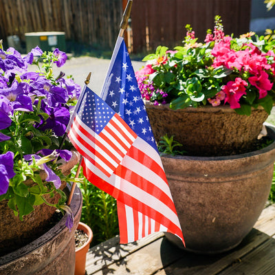 12x18 inch U.S. Stick Flags on wooden sticks, designed for outdoor use, displayed in a festive outdoor setting.