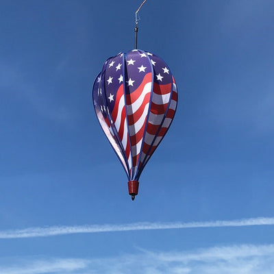 USA Flag 10-Panel Hot Air Balloon spinning in a gentle breeze, showcasing a vibrant American flag design in an outdoor garden setting.