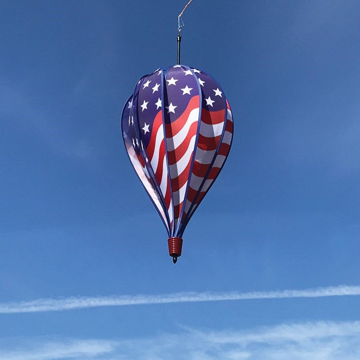 USA Flag 10-Panel Hot Air Balloon spinning in a gentle breeze, showcasing a vibrant American flag design in an outdoor garden setting.