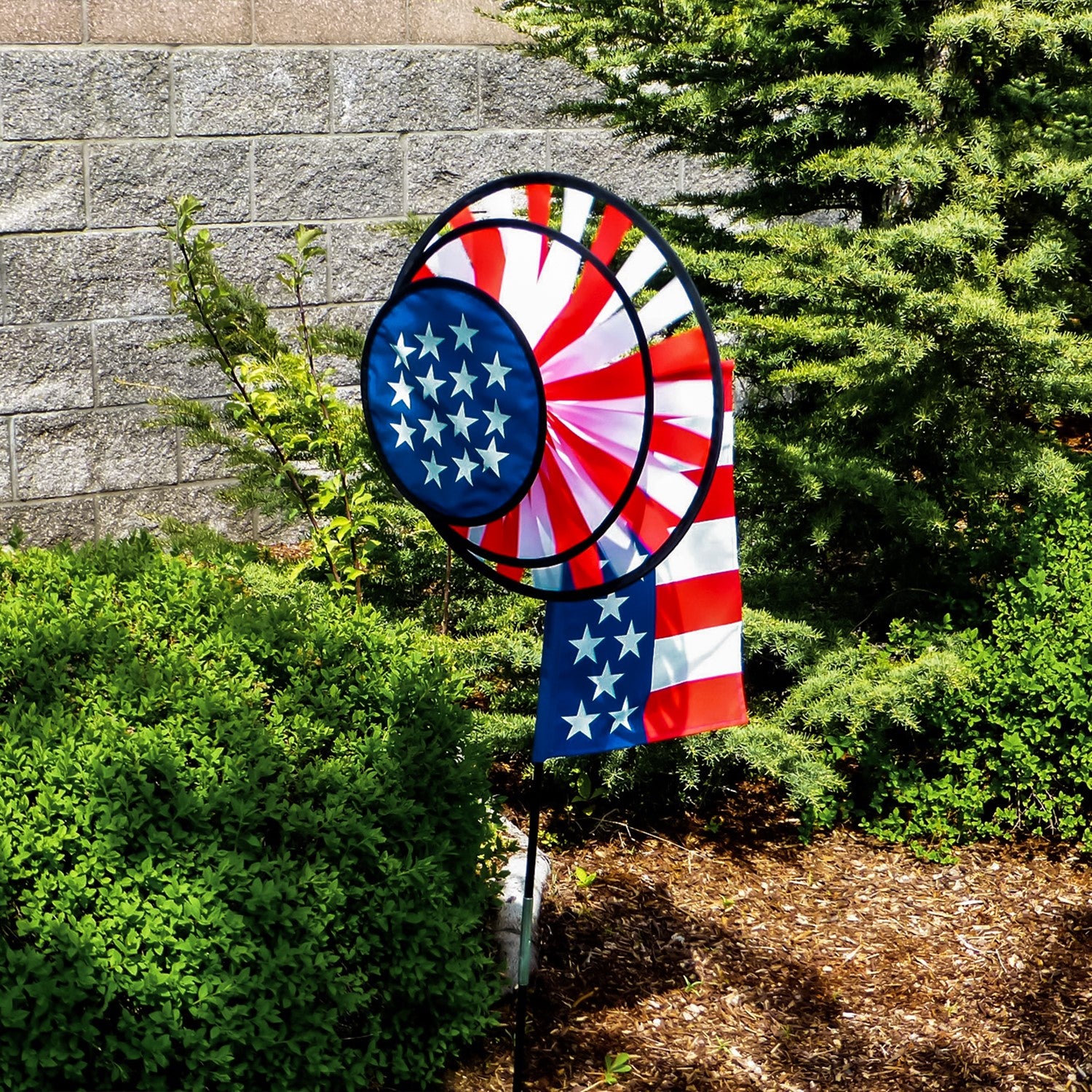 USA Flag Dual Spinner Wheels with red, white and blue design in a garden setting, featuring a garden flag and a robust pole for display.