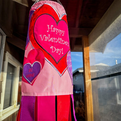 Valentine's Day 40-inch windsock with colorful heart appliques, fluttering gently in the wind, displayed outdoors on a sunny day.