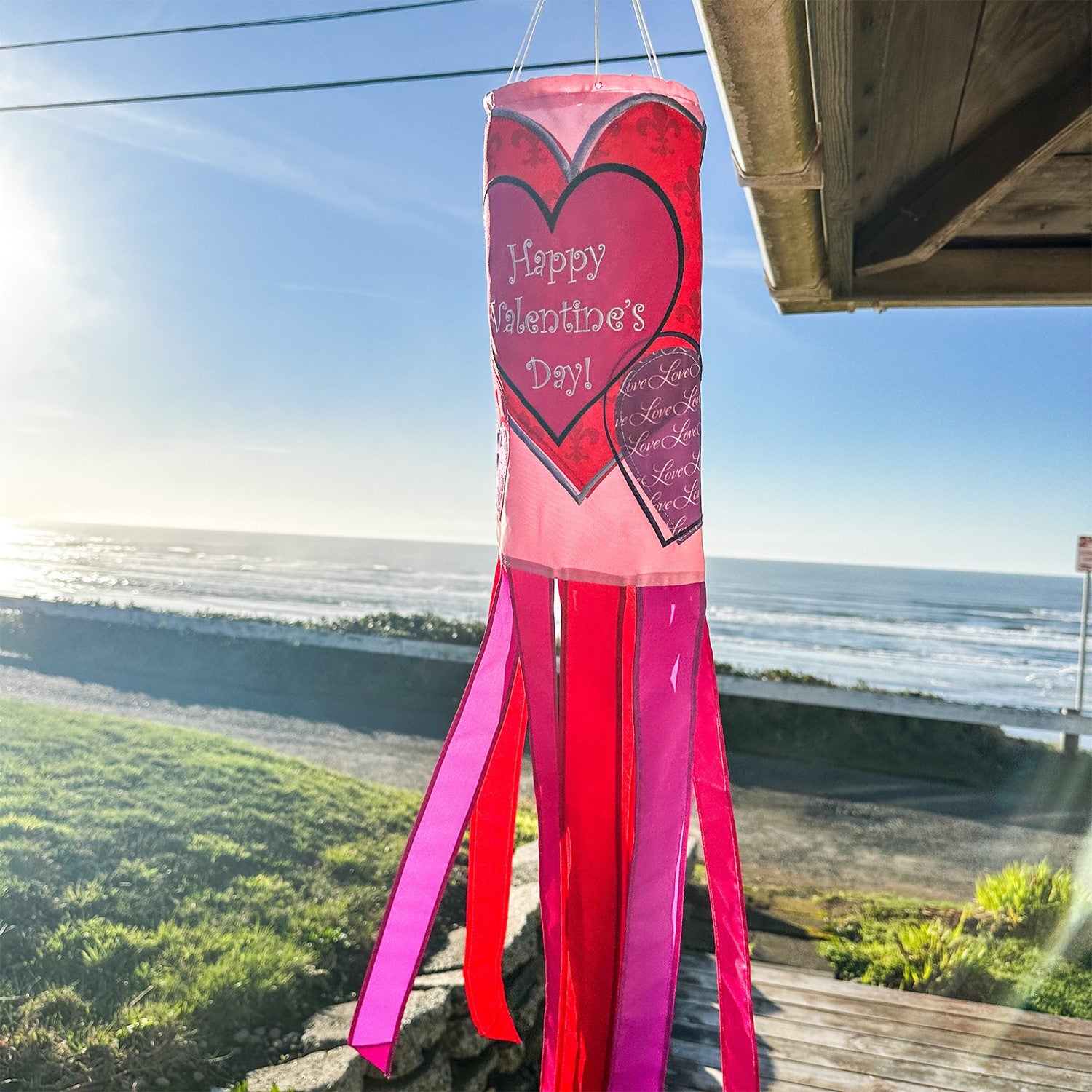Valentine's Day 40-inch windsock with colorful heart appliques, fluttering gently in the wind, displayed outdoors on a sunny day.