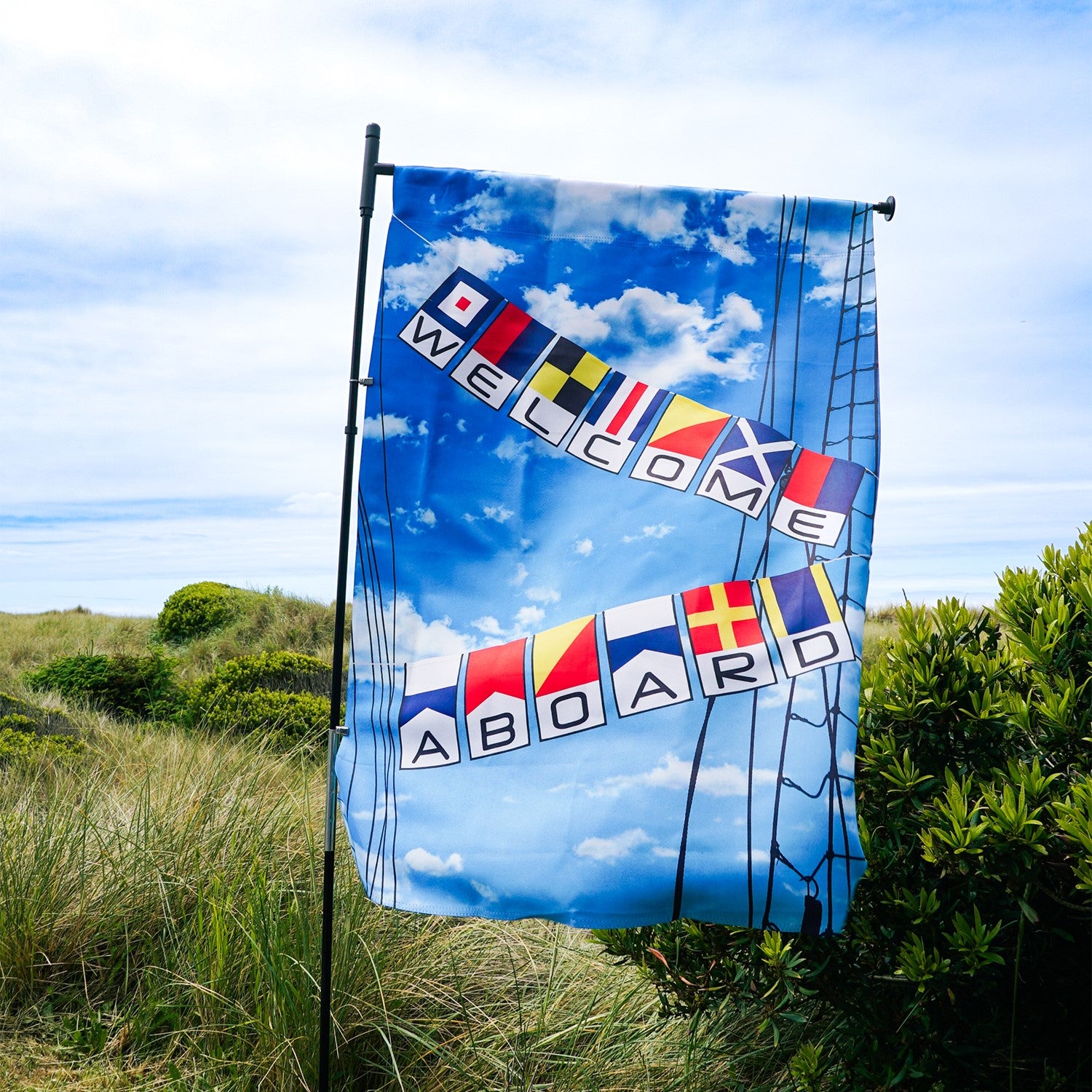 Welcome Aboard Lustre House Banner with double-sided nautical design, displayed on a flagpole in a vibrant outdoor setting.