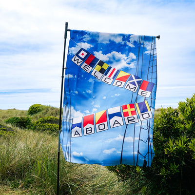 Welcome Aboard Lustre House Banner with double-sided nautical design, displayed on a flagpole in a vibrant outdoor setting.