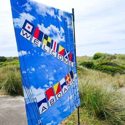 Welcome Aboard Lustre House Banner with double-sided nautical design, displayed on a flagpole in a vibrant outdoor setting.